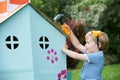 Young Boy Pretending To Fix Cardboard Playhouse