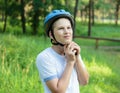 Young boy in puts on helmet in park. Smiling cute boy on bicycle in the forest. Active fun healthy outdoor sport for children. Royalty Free Stock Photo