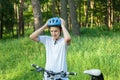 Young boy in puts on helmet in park. Smiling cute boy on bicycle in the forest. Active fun healthy outdoor sport for children.