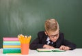 Young boy reading a book near empty green chalkboard Royalty Free Stock Photo