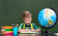 Young boy reading a book near empty green chalkboard Royalty Free Stock Photo