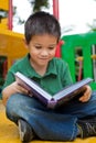 Young boy reading book in a playground