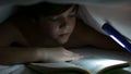 Young boy reading a captivating book at night