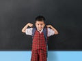 Young boy in red school uniform flexing his muscles in front of the class with smile on his face Royalty Free Stock Photo