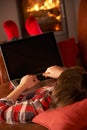 Young Boy Relaxing With Laptop By Cosy Log Fire Royalty Free Stock Photo