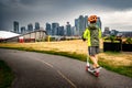 A young boy rides a scooter along a bike path overlooking the downtown skyline and popular landmarks at Scotsman\'s Hill.