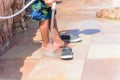 Young boy rinsing off his feet and shoes