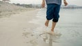 A young boy running barefoot on the sandy beach and enjoying the cool sea water. Fun, happiness, and excitement of a family Royalty Free Stock Photo