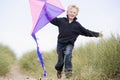 Young boy running on beach with kite smiling Royalty Free Stock Photo