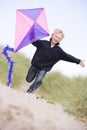 Young boy running on beach with kite smiling Royalty Free Stock Photo