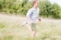 Young boy running in a field smiling Royalty Free Stock Photo