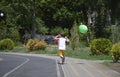 Young boy running with green balloon near tree and grass, wearing shorts Royalty Free Stock Photo