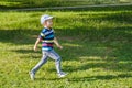 Young boy runs in a green field. Cute child running across park outdoors grass Royalty Free Stock Photo