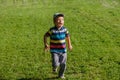 Young boy runs in a green field. Cute child running across park outdoors grass. Royalty Free Stock Photo