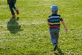 Young boy runs in a green field. Cute child running across park outdoors grass. Royalty Free Stock Photo