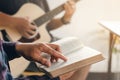 A Young Boy Sat And Read The Bible While His Friend Played Guitar At Church When He Worshiped God. A Small Group Of Christians Or