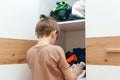 Young boy searching for clothing in messy closet. Mess in the wardrobe. Untidy clutter clothing closet