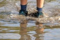 Young boy with short blue trowsers wading with wet socks and wet boots through high tide after a floodwater Royalty Free Stock Photo