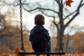 A young boy sits on a swing in a vibrant park, lost in thought, A boy sitting alone on a swing, lost in thought Royalty Free Stock Photo