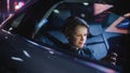 Young Boy is Sitting on Backseat of a Car, Commuting Home at Night. Passenger Watching Funny