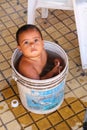 Young boy sitting in a bucket with water in the street of Asuncion, Paraguay