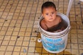 Young boy sitting in a bucket with water in the street of Asuncion, Paraguay Royalty Free Stock Photo