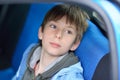 Young boy sitting in the car. Cute attractive 11 years old boy inside auto. Kid`s portrait in motor vehicle. Young automobile
