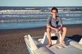 Young boy sitting on catamaran at the summer beach. Cute spectacled smiling happy 12 years old boy at seaside, looking at camera. Royalty Free Stock Photo