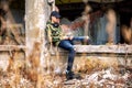 Young boy sitting on a crumbling building and using smarthphone