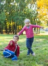 Young boy sitting grass, showing thumb up and pretty girl thump down in autumn park Royalty Free Stock Photo