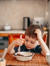 Young boy sitting on the kitchen holds fork and does not want to eat Royalty Free Stock Photo