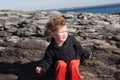 Young boy sitting near rocks at ocean Royalty Free Stock Photo