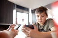 Young boy sitting with parent using mobile phone,Man hand holding smart phone ordering food in restaurant,Kid playing game or Royalty Free Stock Photo