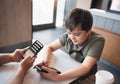 Young boy sitting with parent using mobile phone,Man hand holding smart phone ordering food in restaurant,Kid playing game or Royalty Free Stock Photo