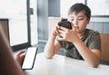 Young boy sitting with parent using mobile phone,Man hand holding smart phone ordering food in restaurant,Kid playing game or Royalty Free Stock Photo