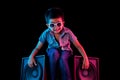 Young boy sitting on speakers looking cool with vivid red and blue colored lighting