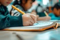 A young boy is sitting at a table, writing in a notebook with a pencil Royalty Free Stock Photo
