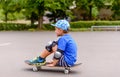 Young boy sitting watching on his skateboard Royalty Free Stock Photo