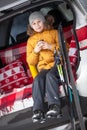 Young boy skier sitting in car boot and drinking tea from mug. Winter Royalty Free Stock Photo