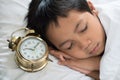 Young boy sleeping with alarm clock Royalty Free Stock Photo