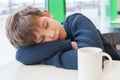 Young boy is sleeping on table with empty cup Royalty Free Stock Photo