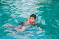 A young boy smiling swimming and having fun in pool at waterpark