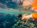 Young boy Snorkel swim in shallow water with coral school of fish