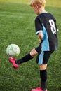 Young boy with soccer ball is in motion on green grass background Royalty Free Stock Photo