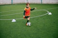 Young boy with soccer ball training at stadium. Football soccer player in motion on green grass sports field. Royalty Free Stock Photo