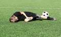 A young boy soccer player injured his leg during the match and ball on the field. Kids injury in sport concept. Copy Royalty Free Stock Photo