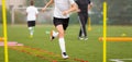 Young boy in soccer shoes cleats running through training ladder. Coach in the background Royalty Free Stock Photo