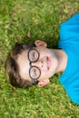 Young boy in spectacle lying on grass Royalty Free Stock Photo