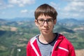 Young boy spectacled looking at camera outdoor over San Marino city-state. Vision, eyesight, sight, diopters, spectacles