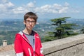 Young boy spectacled looking at camera outdoor over San Marino city-state. Vision, eyesight, sight, diopters, spectacles